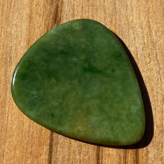 Pounamu guitar pick hand-carved from New Zealand Marsden flower jade pounamu (greenstone). Front.