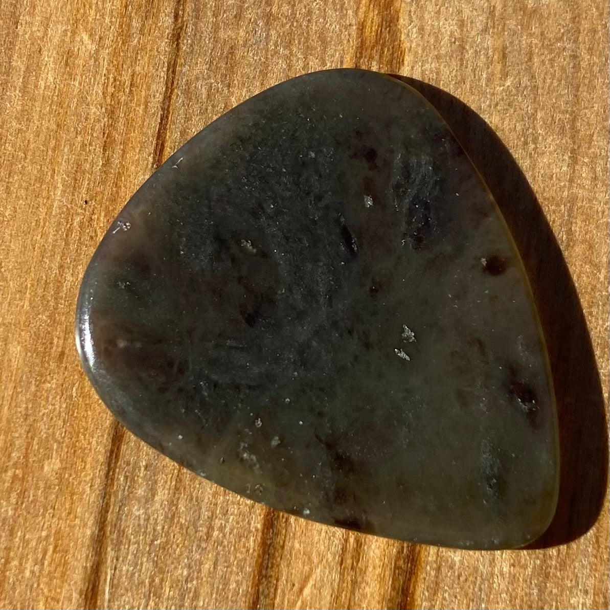 Guitar pick hand-carved from New Zealand Kawakawa Greenstone pounamu (greenstone). Front.