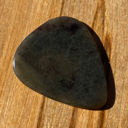 Guitar pick hand-carved from New Zealand Kawakawa Greenstone pounamu (greenstone). Front.