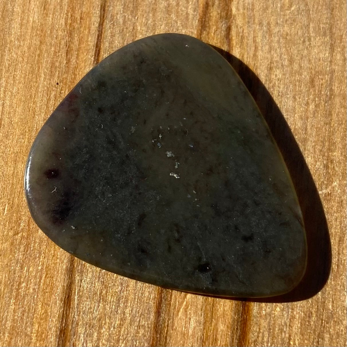 Guitar pick hand-carved from New Zealand Kawakawa Greenstone pounamu (greenstone). Front.