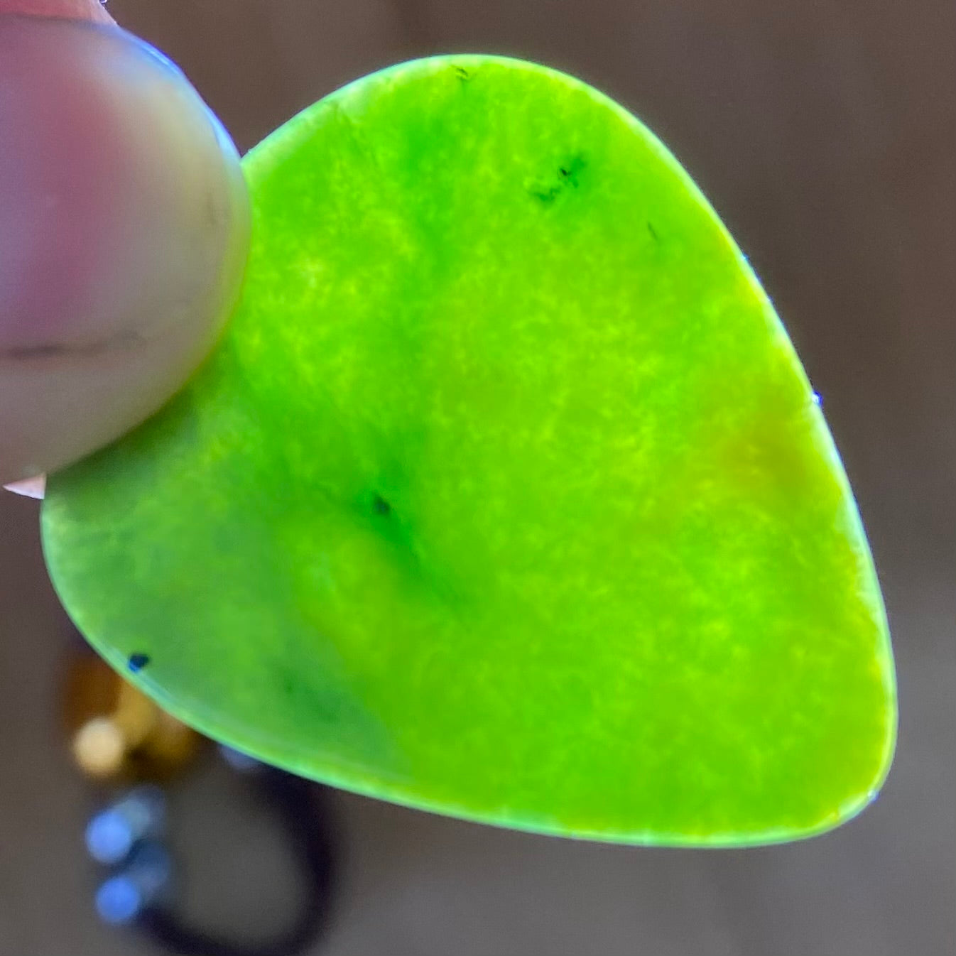 Pounamu guitar pick hand-carved from New Zealand Marsden flower jade pounamu (greenstone). Translucency.