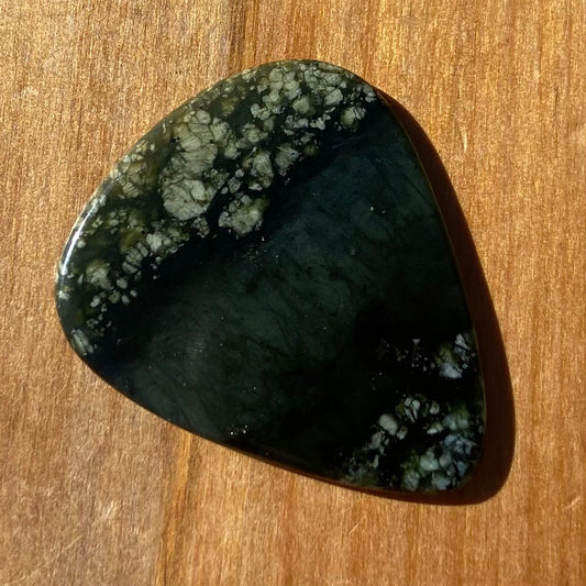Guitar pick hand-carved from New Zealand tangiwai pounamu (greenstone). Front.