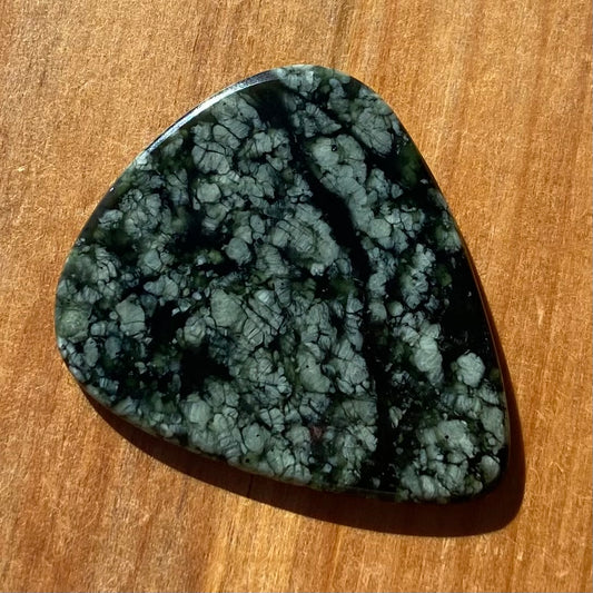 Guitar pick hand-carved from New Zealand tangiwai pounamu (greenstone). Front.