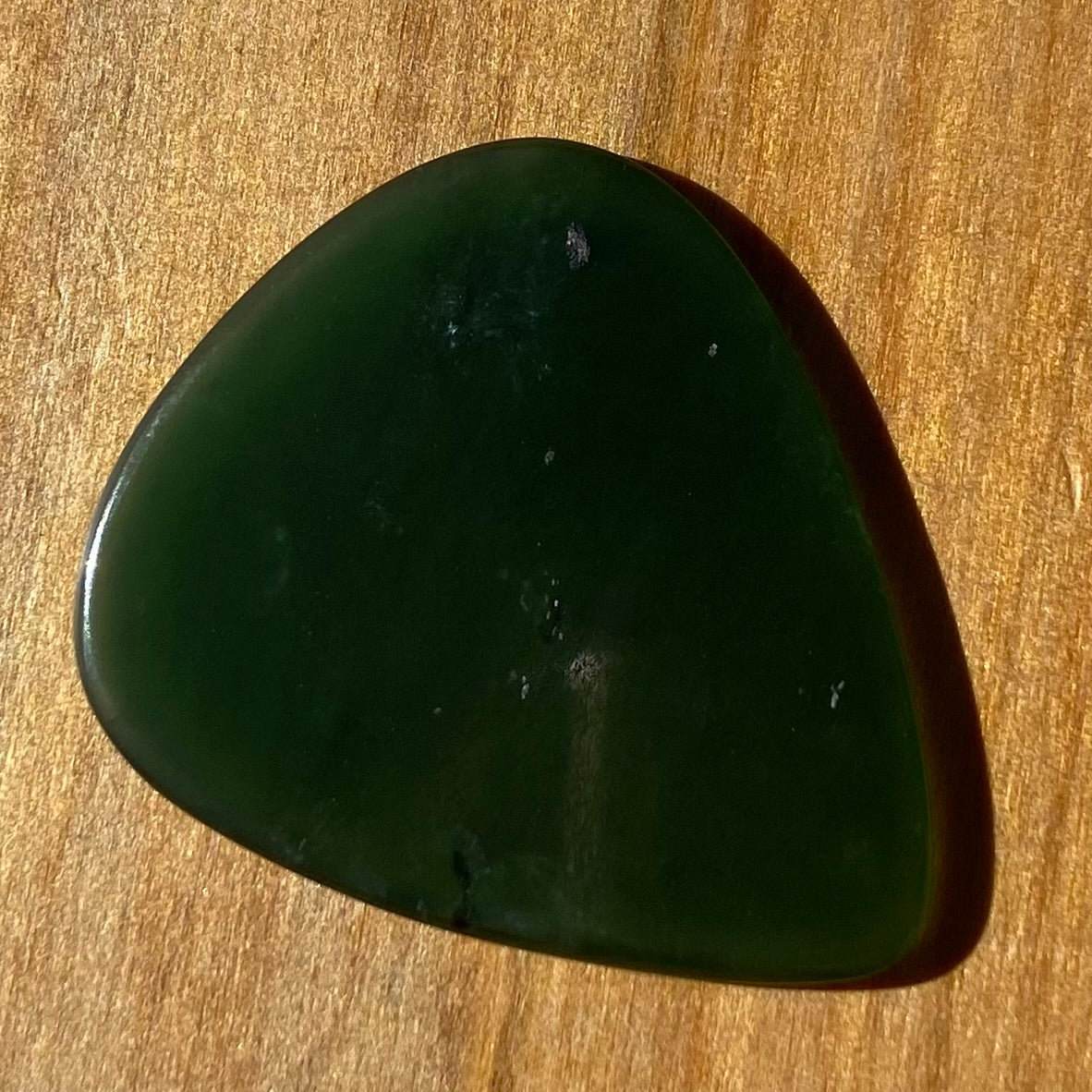 Guitar pick hand-carved from New Zealand Kahurangi Greenstone pounamu (greenstone). Front.