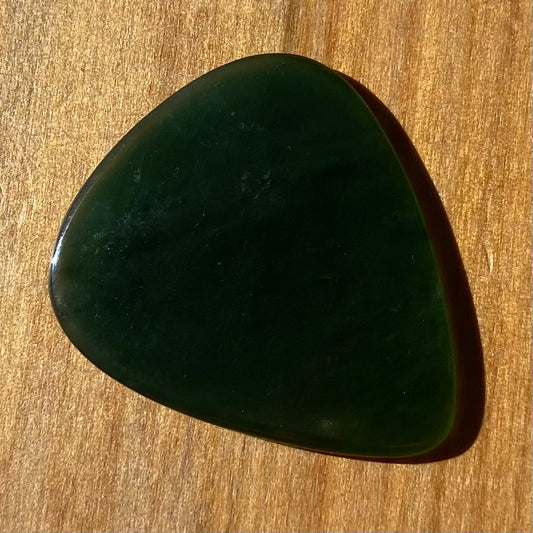 Guitar pick hand-carved from New Zealand Kahurangi Greenstone pounamu (greenstone). Front.