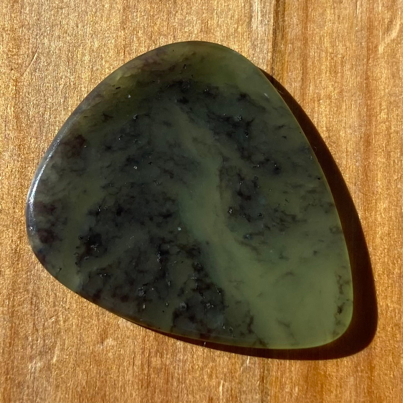 Guitar pick hand-carved from New Zealand Kawakawa Greenstone pounamu (greenstone). Front.