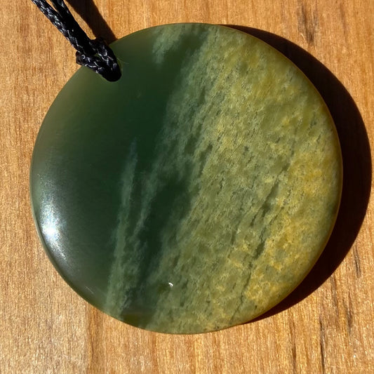 Pounamu porohita, disc, circle of life pendant from New Zealand Marsden Flower Jade pounamu (greenstone). Front.
