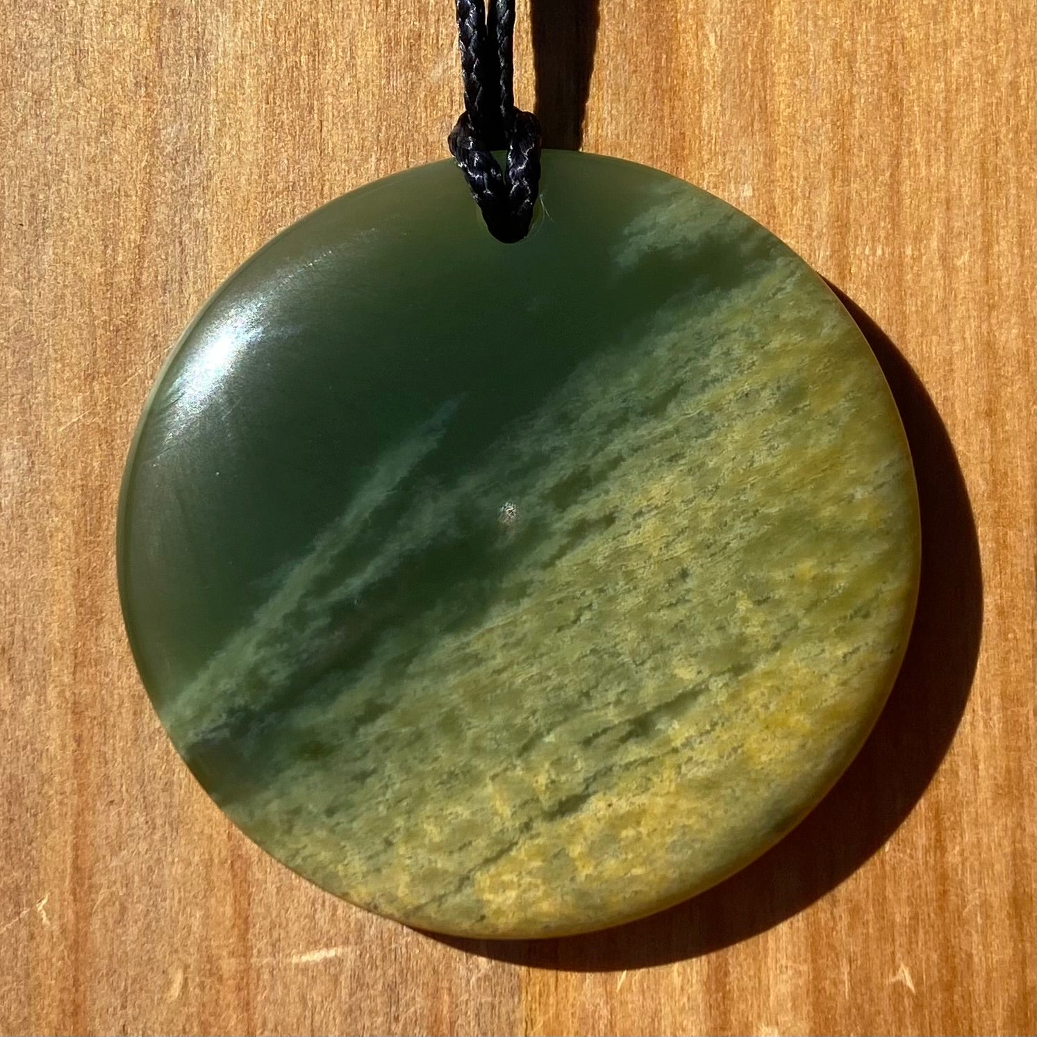 Pounamu porohita, disc, circle of life pendant from New Zealand Marsden Flower Jade pounamu (greenstone). Front.