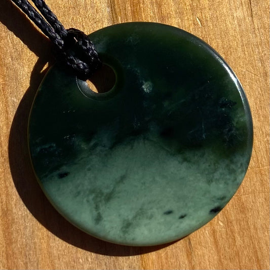 Pounamu porohita, disc, circle of life pendant from New Zealand Kawakawa pounamu (greenstone). Front.