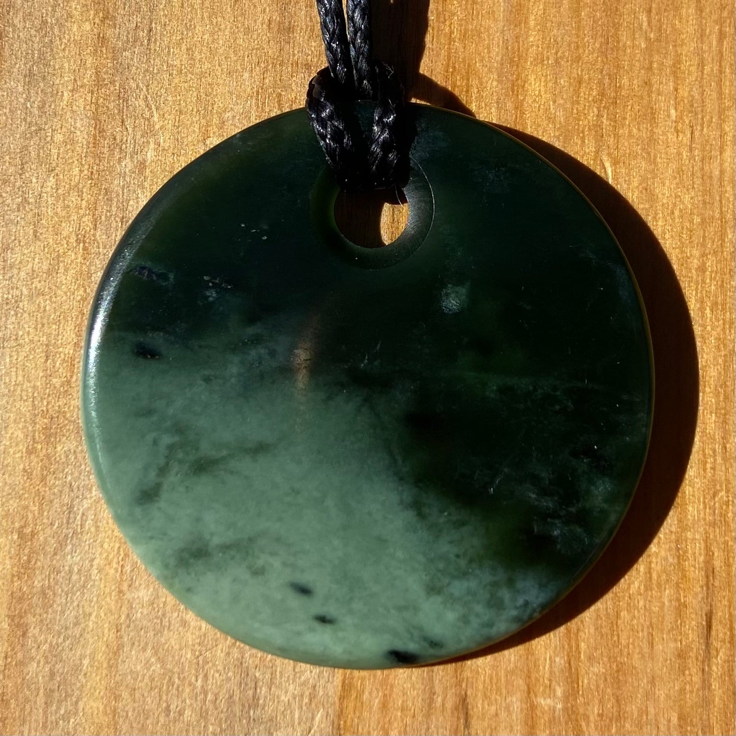 Pounamu porohita, disc, circle of life pendant from New Zealand Kawakawa pounamu (greenstone). Front.