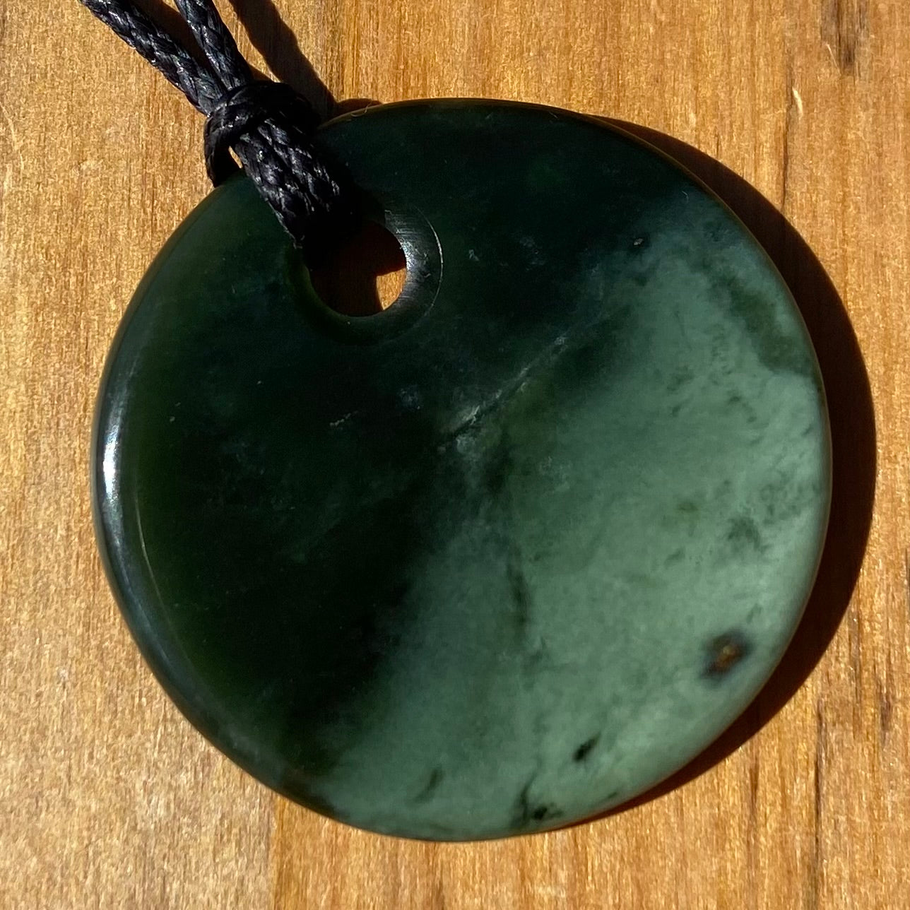 Pounamu porohita, disc, circle of life pendant from New Zealand Kawakawa pounamu (greenstone). Front.