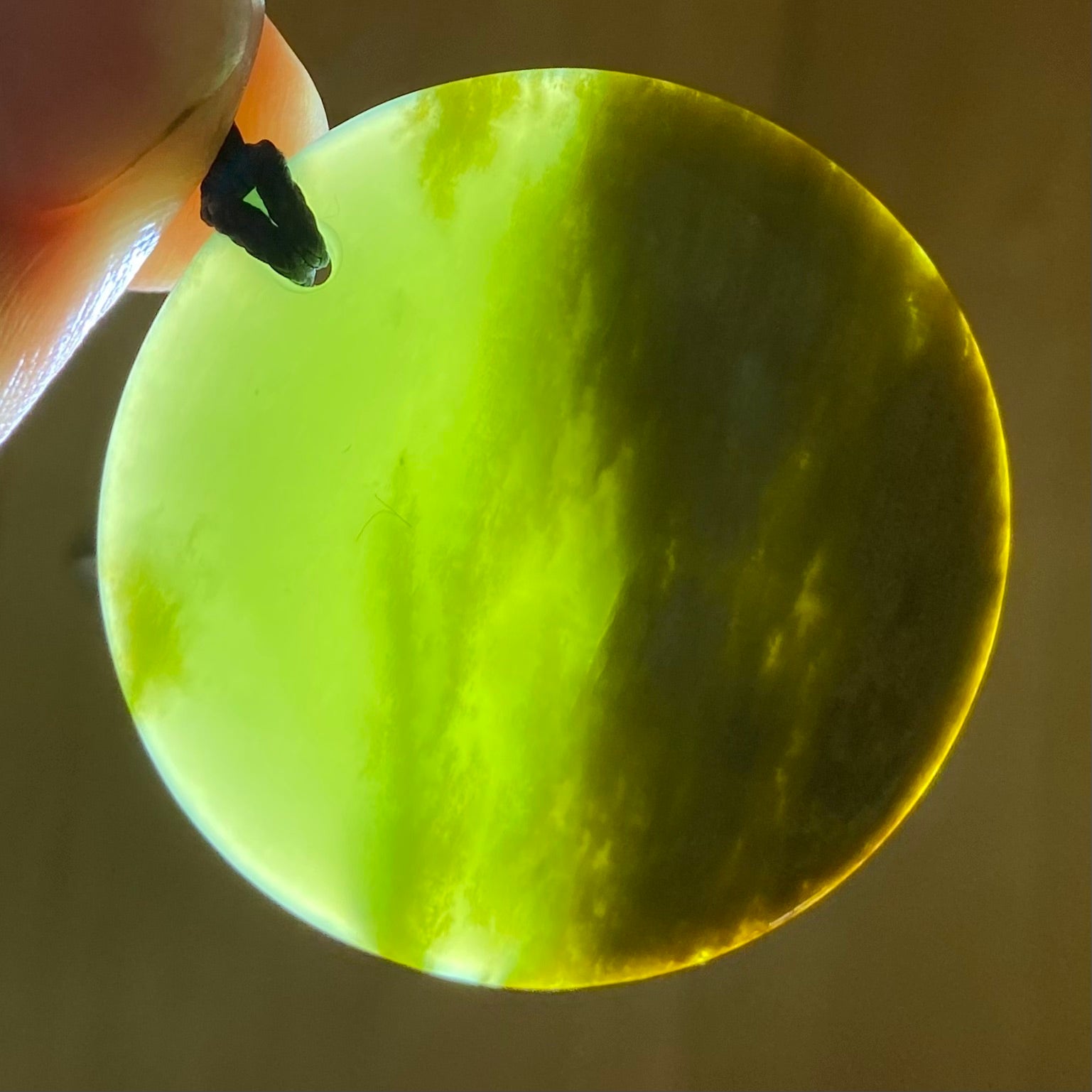 Pounamu porohita, disc, circle of life pendant from New Zealand Marsden Flower Jade pounamu (greenstone). Translucency.
