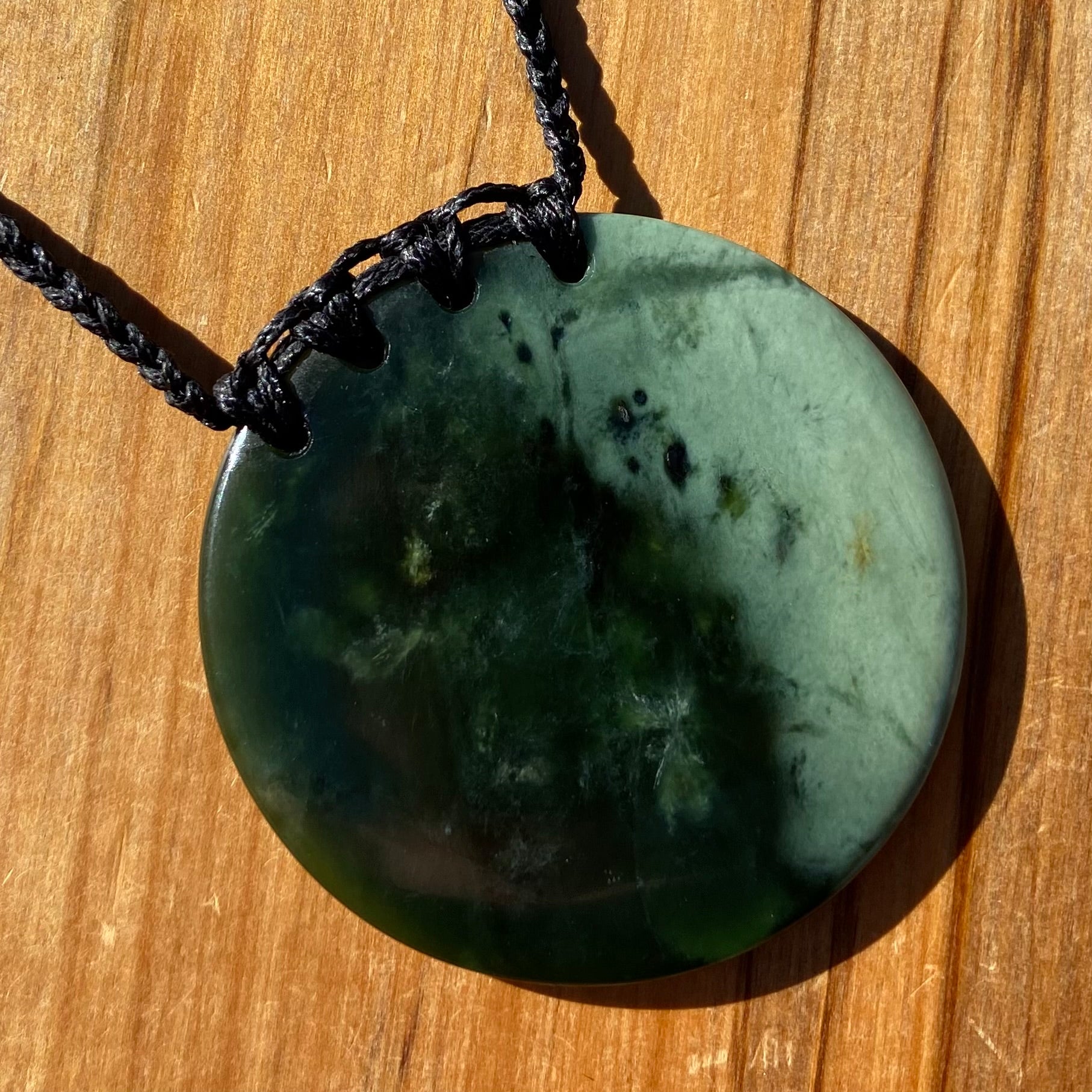 Pounamu porohita, disc, circle of life pendant from New Zealand Kawakawa pounamu (greenstone). Front.