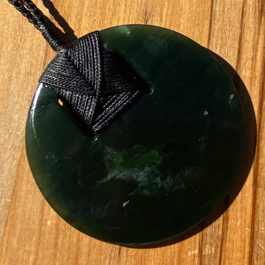 Pounamu porohita, disc, circle of life pendant from New Zealand Kawakawa pounamu (greenstone). Front.