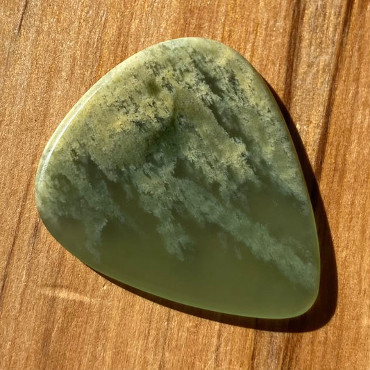 Pounamu guitar pick hand-carved from New Zealand Marsden flower jade pounamu (greenstone). Front.