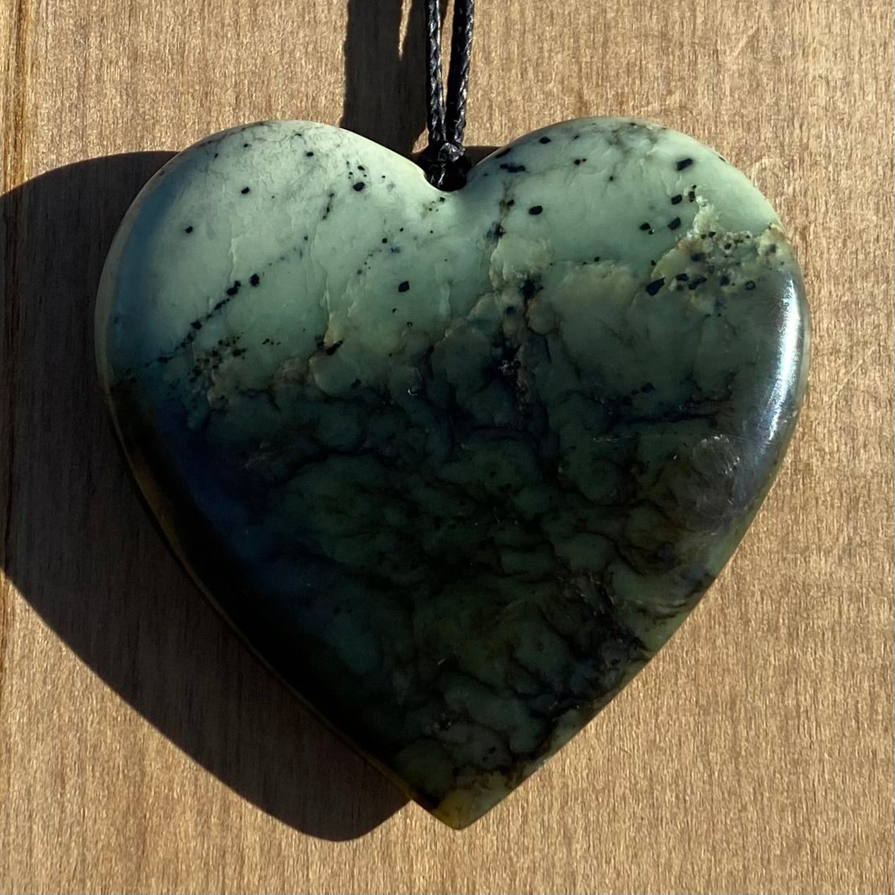 Heart pendant hand-carved from New Zealand kawawkawa pounamu (greenstone). Front.