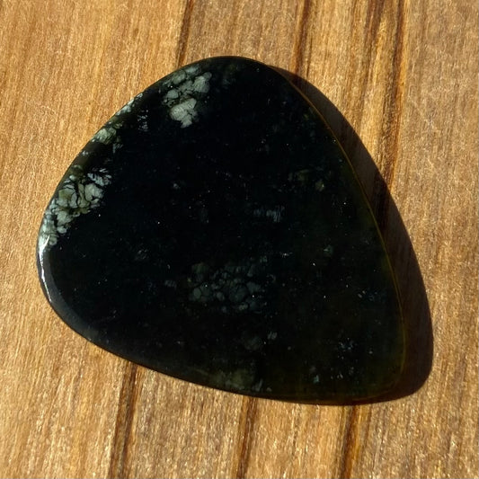 Guitar pick hand-carved from New Zealand tangiwai pounamu (greenstone). Front.