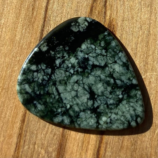 Guitar pick hand-carved from New Zealand tangiwai pounamu (greenstone). Front.