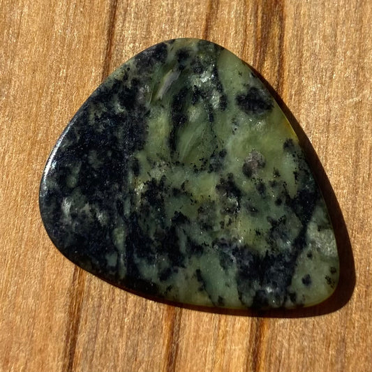 Guitar pick hand-carved from New Zealand Douglas Creek pounamu (greenstone). Front.
