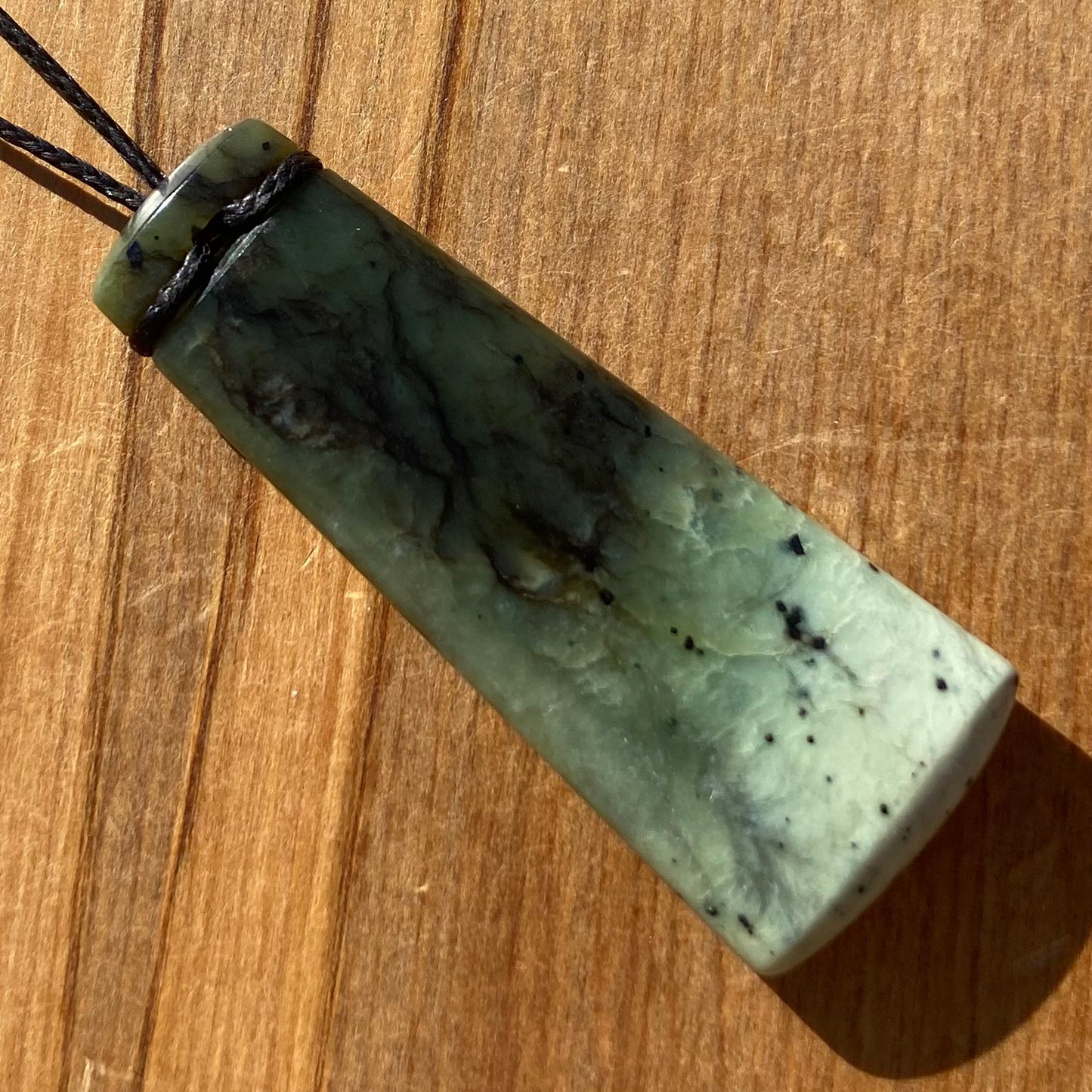 Pounamu toki pendant hand-carved from New Zealand Kawakawa pounamu (greenstone). Back.