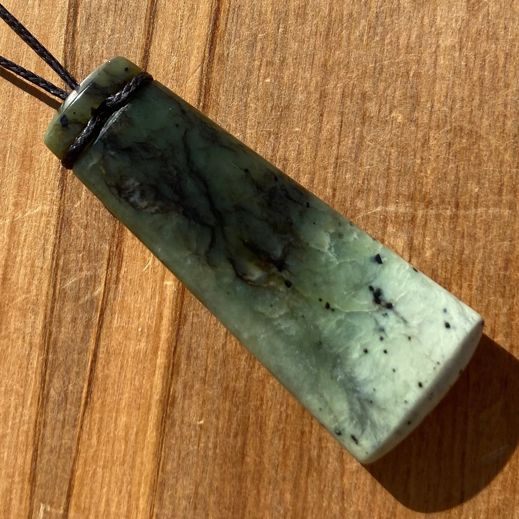 Pounamu toki pendant hand-carved from New Zealand Kawakawa pounamu (greenstone). Back.