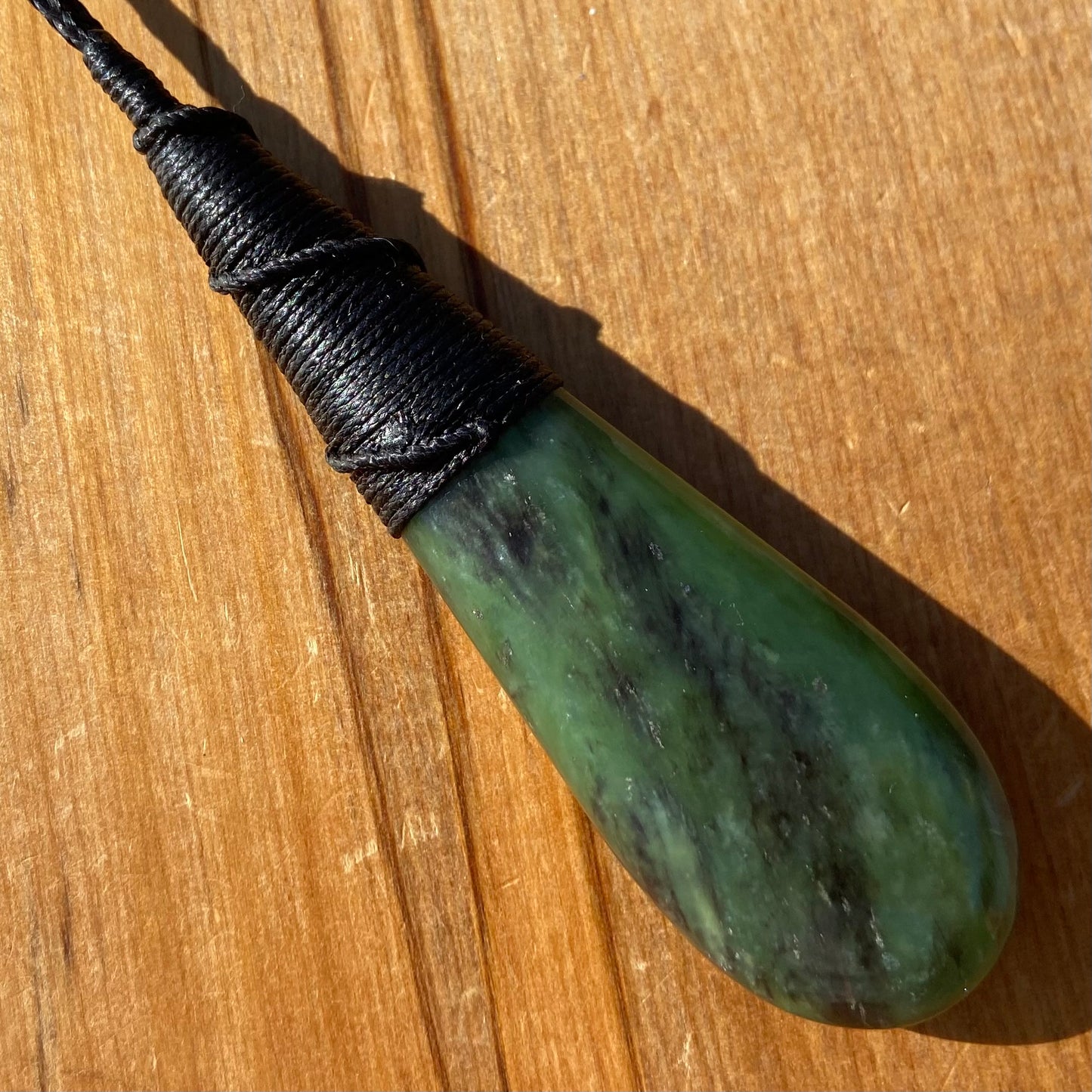 Bound roimata (teardrop) pendant hand-carved from New Zealand Kawakawa pounamu (greenstone). Back.