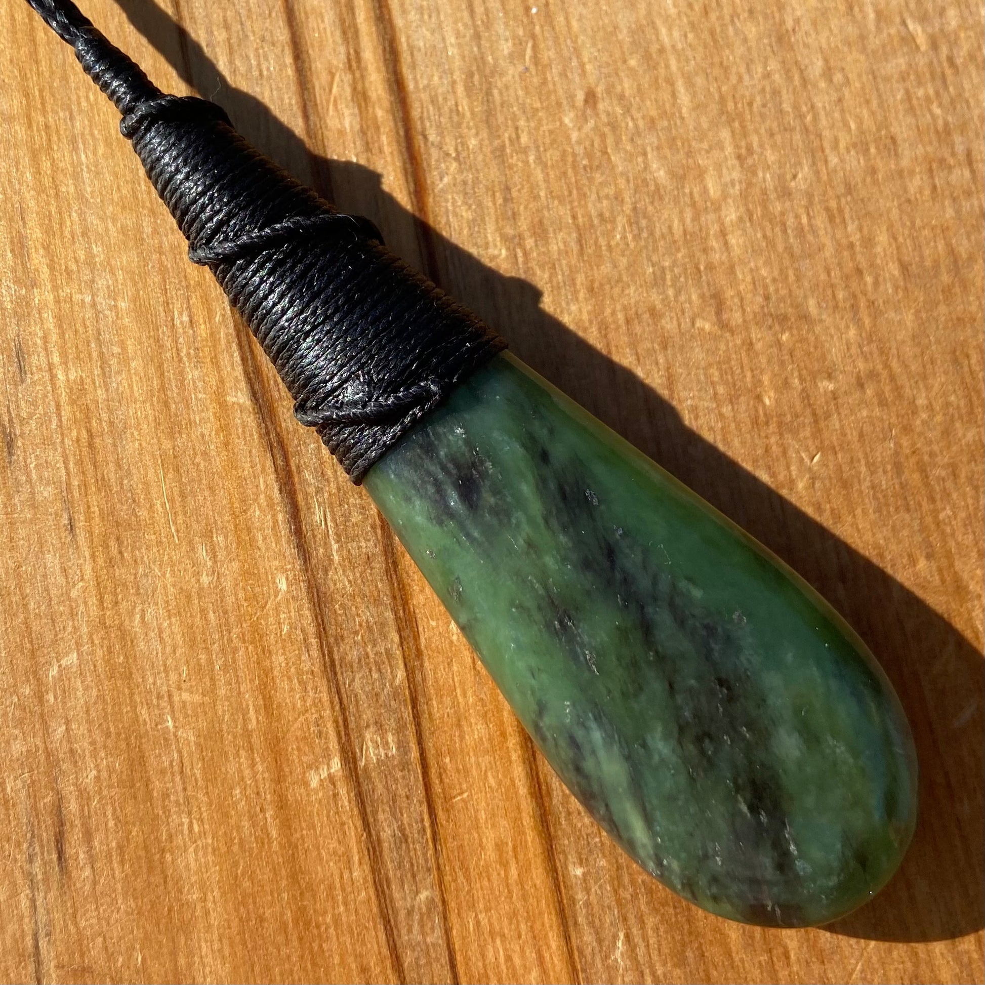 Bound roimata (teardrop) pendant hand-carved from New Zealand Kawakawa pounamu (greenstone). Back.