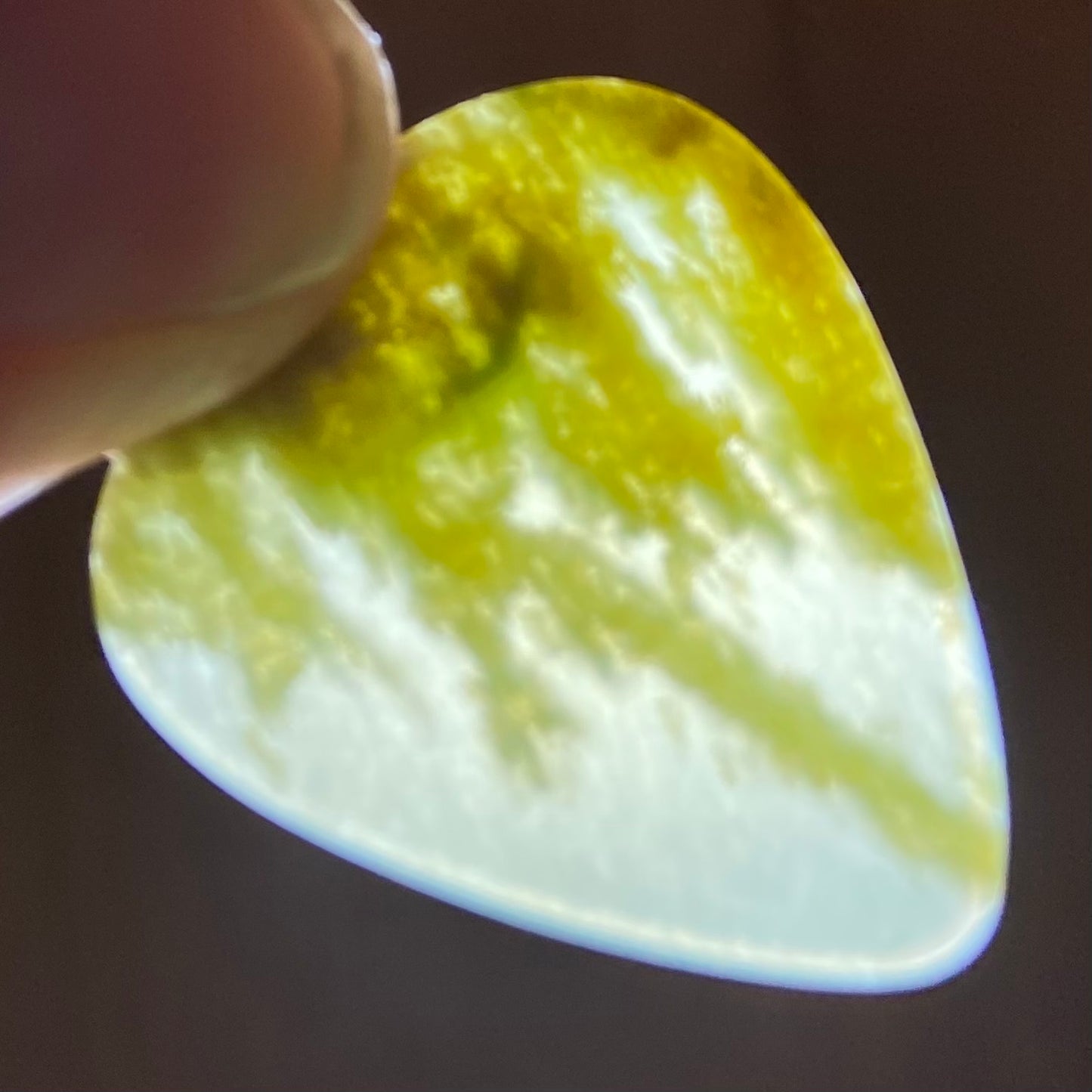 Pounamu guitar pick hand-carved from New Zealand Marsden flower jade pounamu (greenstone). Translucency.