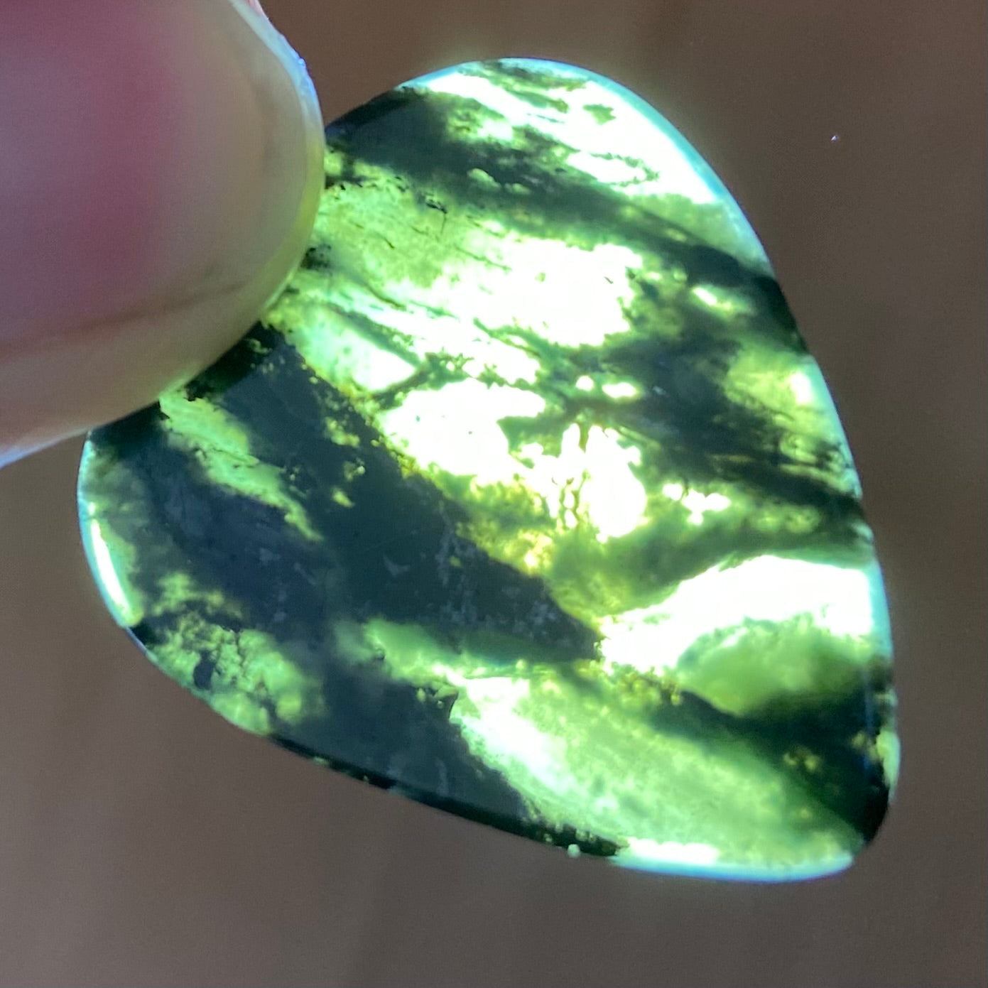 Guitar pick hand-carved from New Zealand Douglas Creek pounamu (greenstone). Translucency.