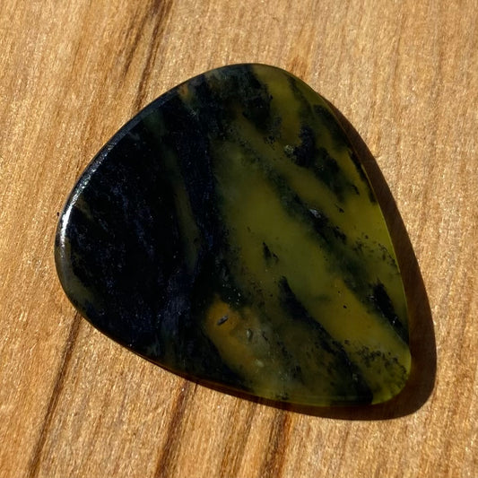 Guitar pick hand-carved from New Zealand Douglas Creek pounamu (greenstone). Front.