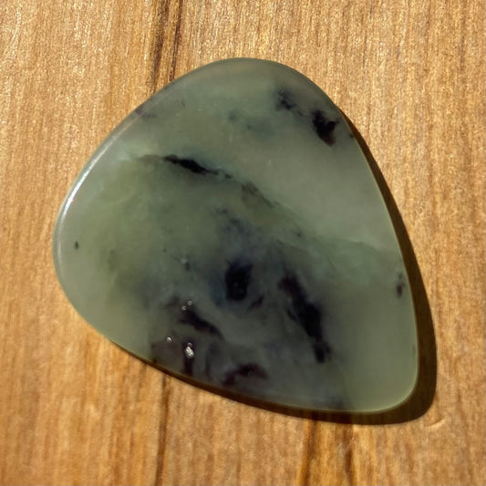 Guitar pick hand-carved from New Zealand Inanga Greenstone pounamu (greenstone). Front.