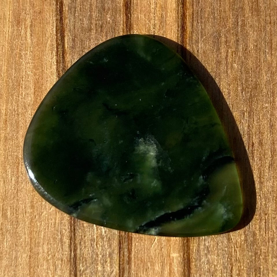 Guitar pick hand-carved from New Zealand Kawakawa Greenstone pounamu (greenstone). Front.