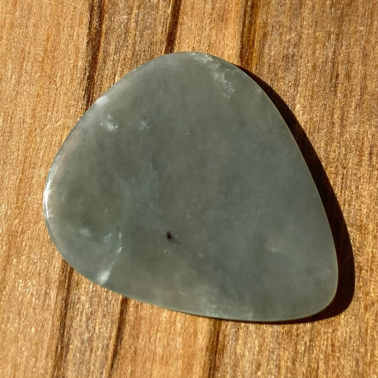Guitar pick hand-carved from New Zealand Inanga Greenstone pounamu (greenstone). Back.