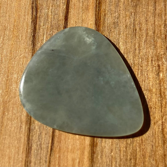 Guitar pick hand-carved from New Zealand Inanga Greenstone pounamu (greenstone). Front.