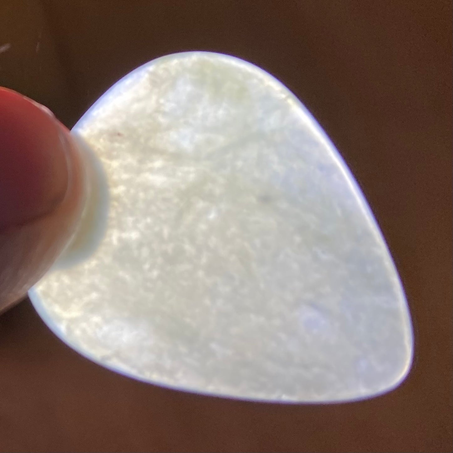 Guitar pick hand-carved from New Zealand Inanga Greenstone pounamu (greenstone). Translucency. 