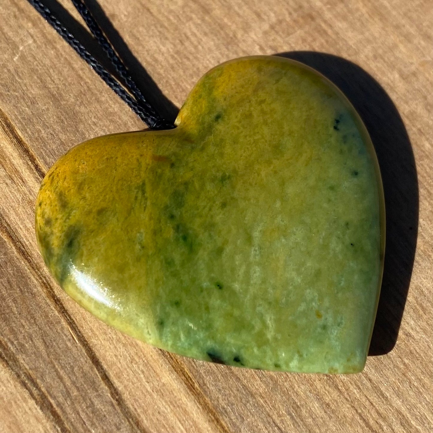 Heart shape pendant carved from New Zealand Marsden Flower Jade (greenstone). Angle.