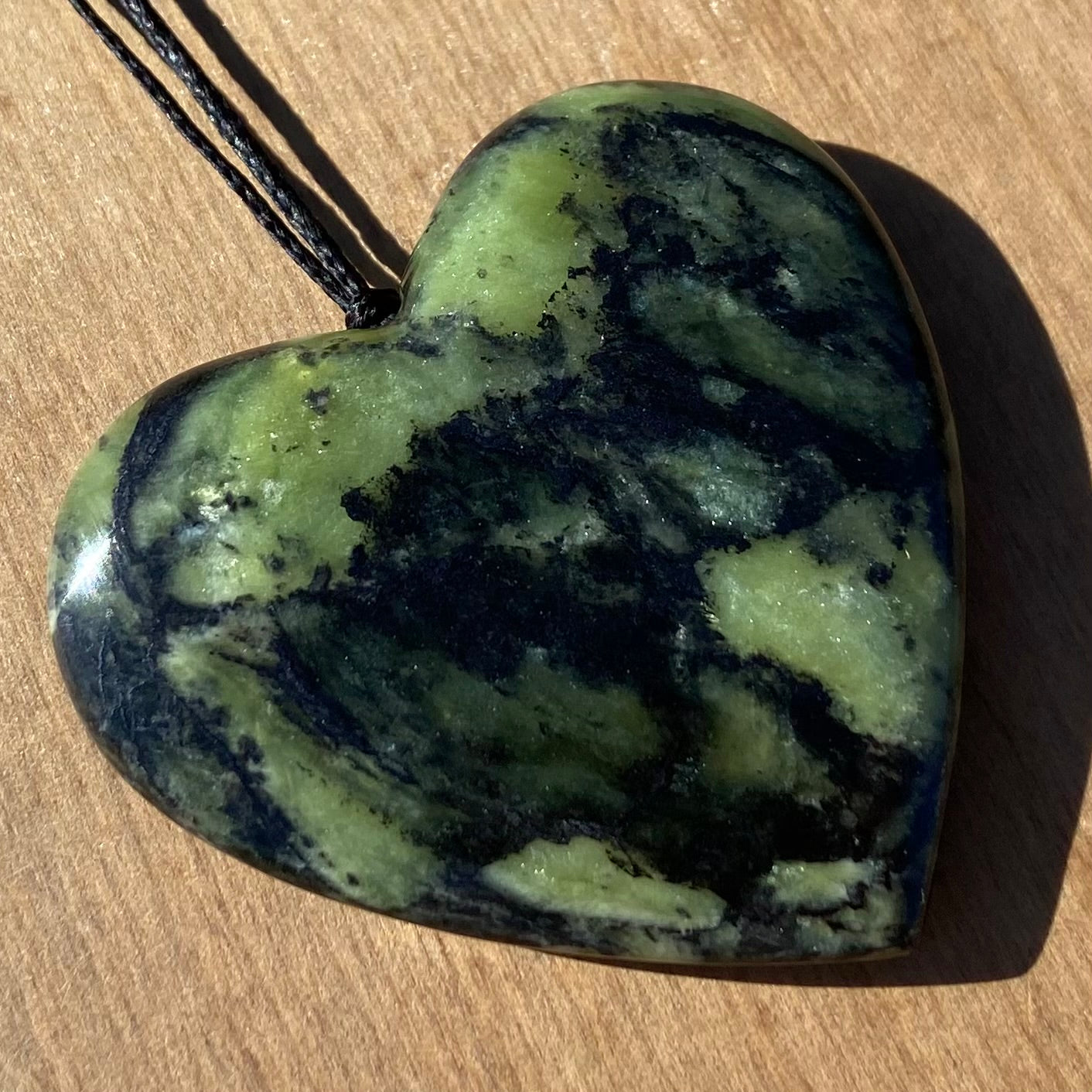 Heart shape pendant carved from New Zealand Douglas Creek pounamu (greenstone). Angle.