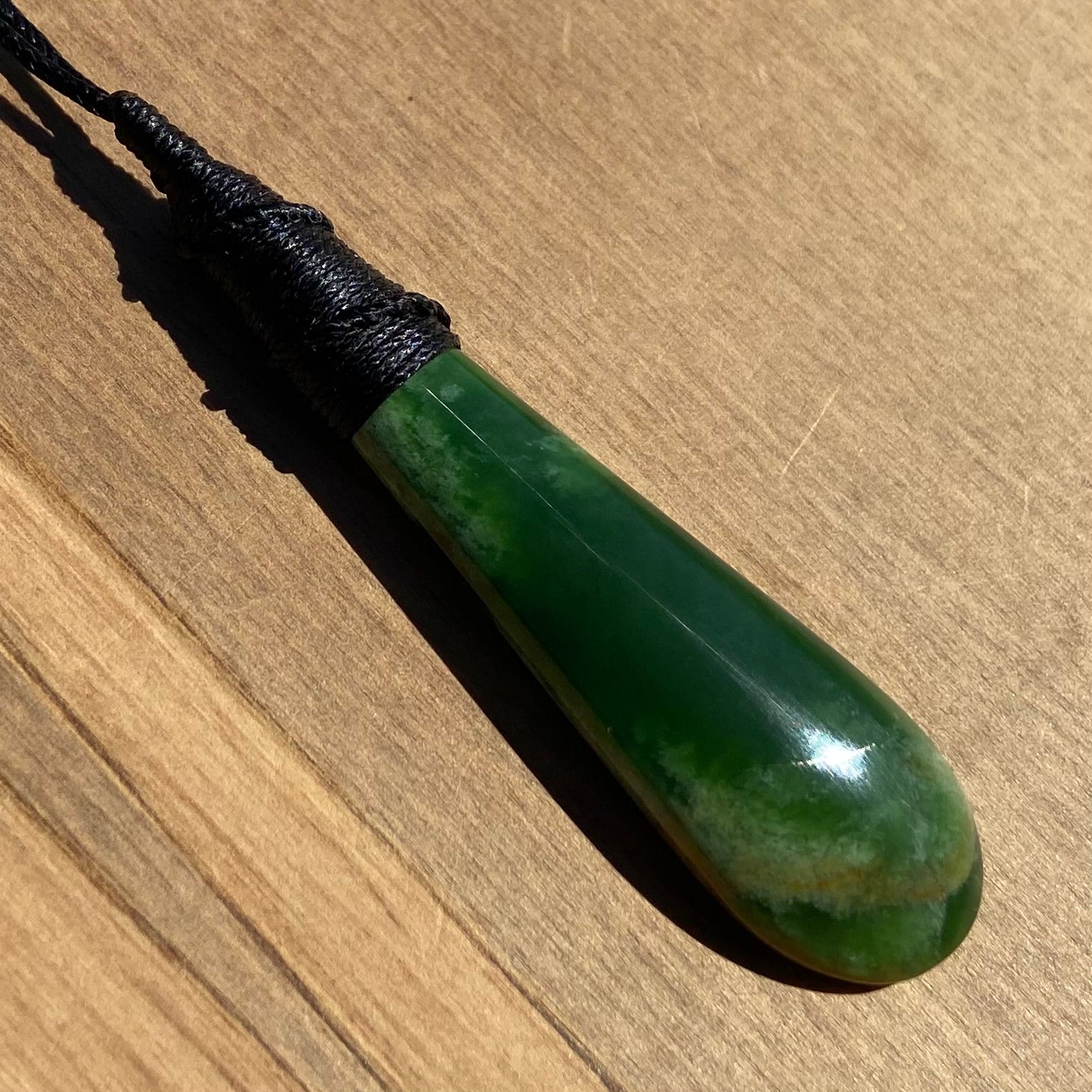 Bound roimata teardrop pendant carved from New Zealand Marsden Flower Jade (greenstone). Front angle