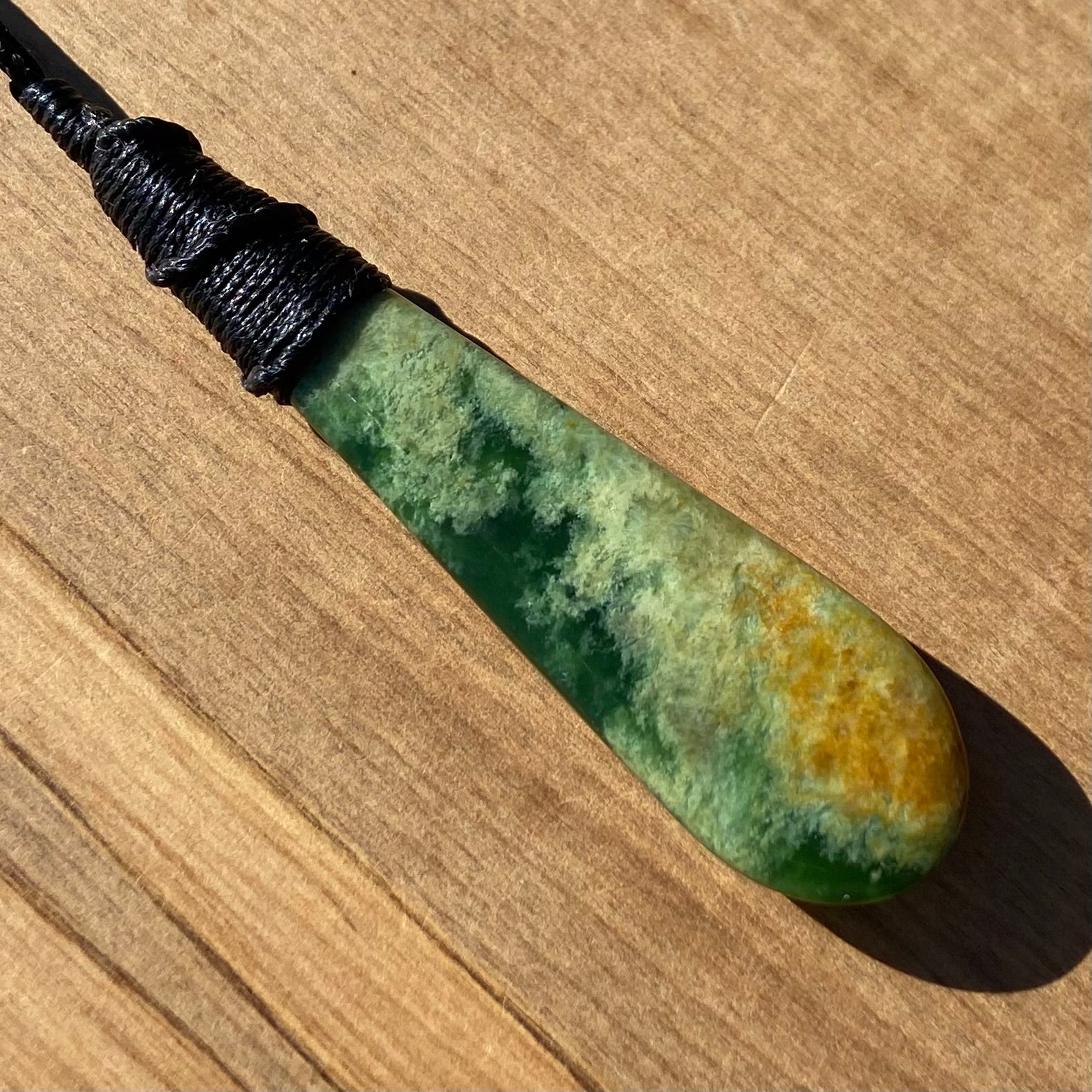 Bound roimata teardrop pendant carved from New Zealand Marsden Flower Jade (greenstone). Back angle.