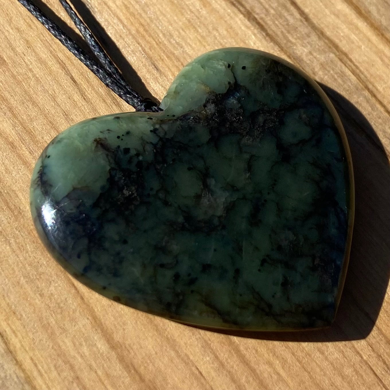 Heart pendant hand-carved from New Zealand Kawakawa pounamu (greenstone). Angle.