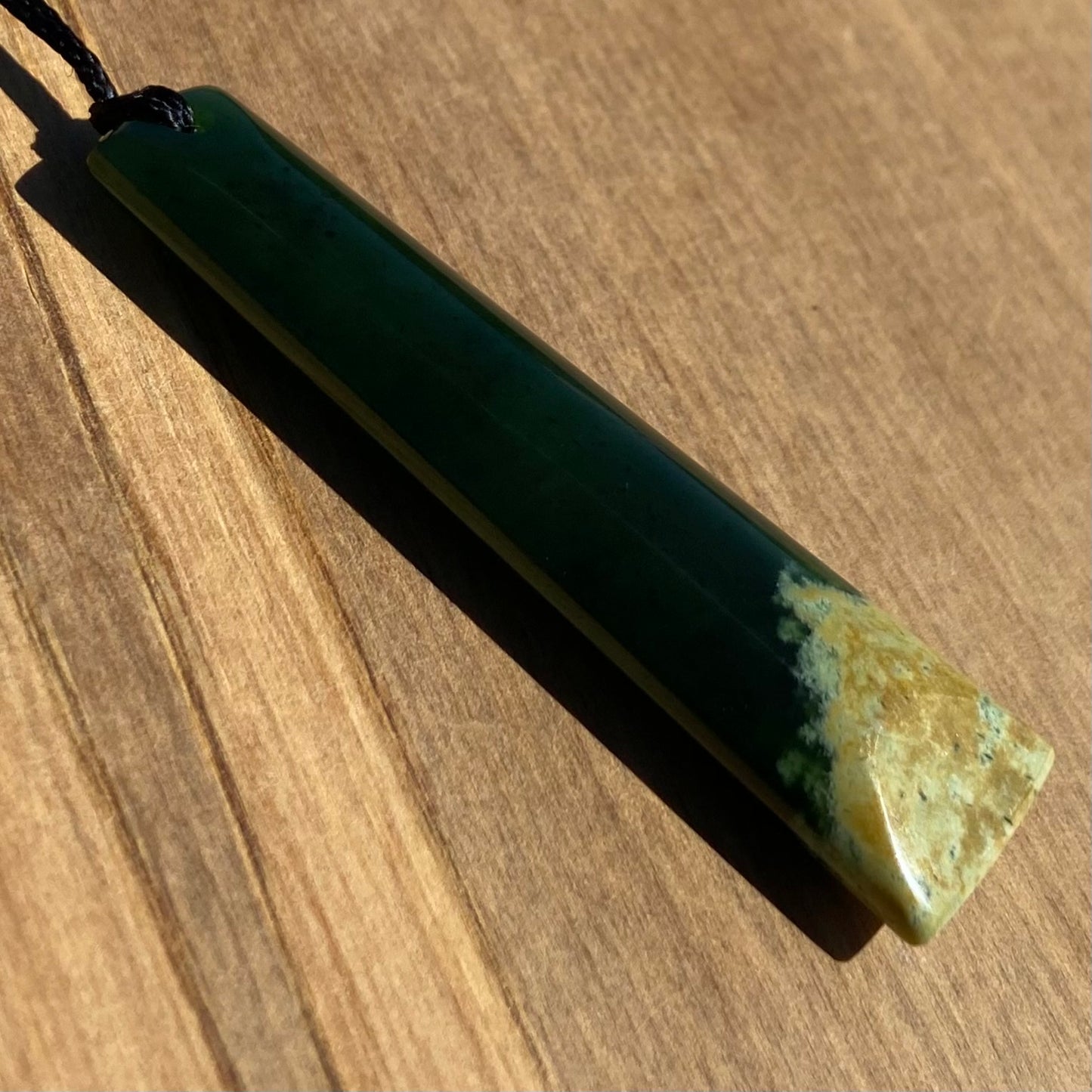 Bound toki pendant hand-carved from New Zealand Marsden Flower Jade pounamu (greenstone). Angle.