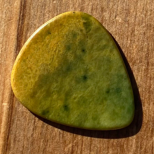 Pounamu guitar pick hand-carved from New Zealand Marsden flower jade pounamu (greenstone). Front.