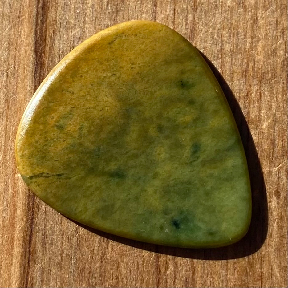 Pounamu guitar pick hand-carved from New Zealand Marsden flower jade pounamu (greenstone). Front.
