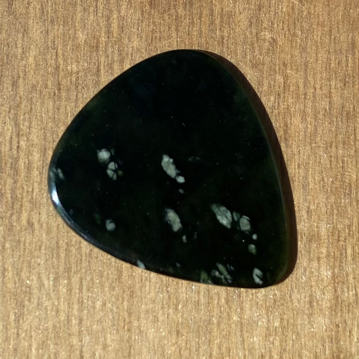 Guitar pick hand-carved from New Zealand tangiwai pounamu (greenstone). Back.