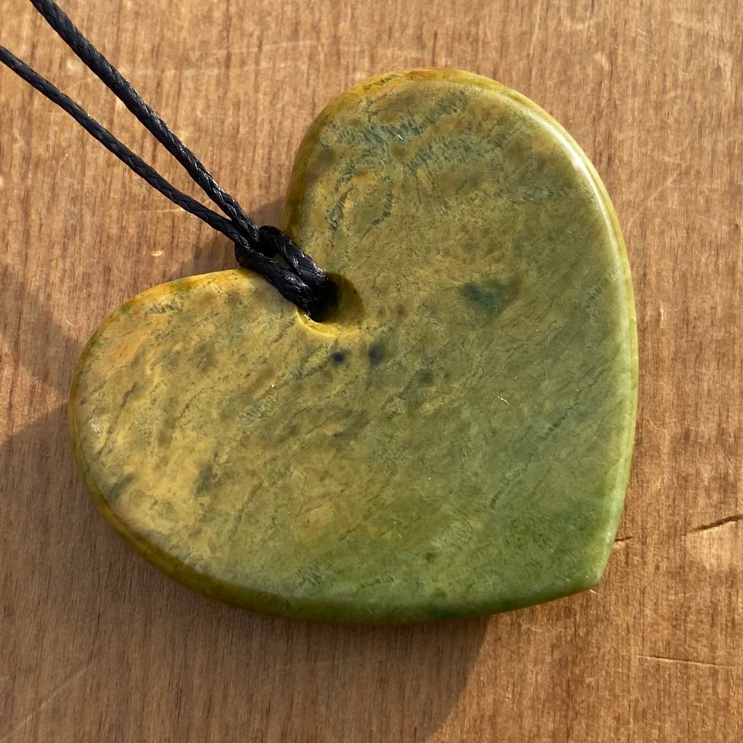 Heart shape pendant carved from New Zealand Marsden Flower Jade (greenstone). Back.