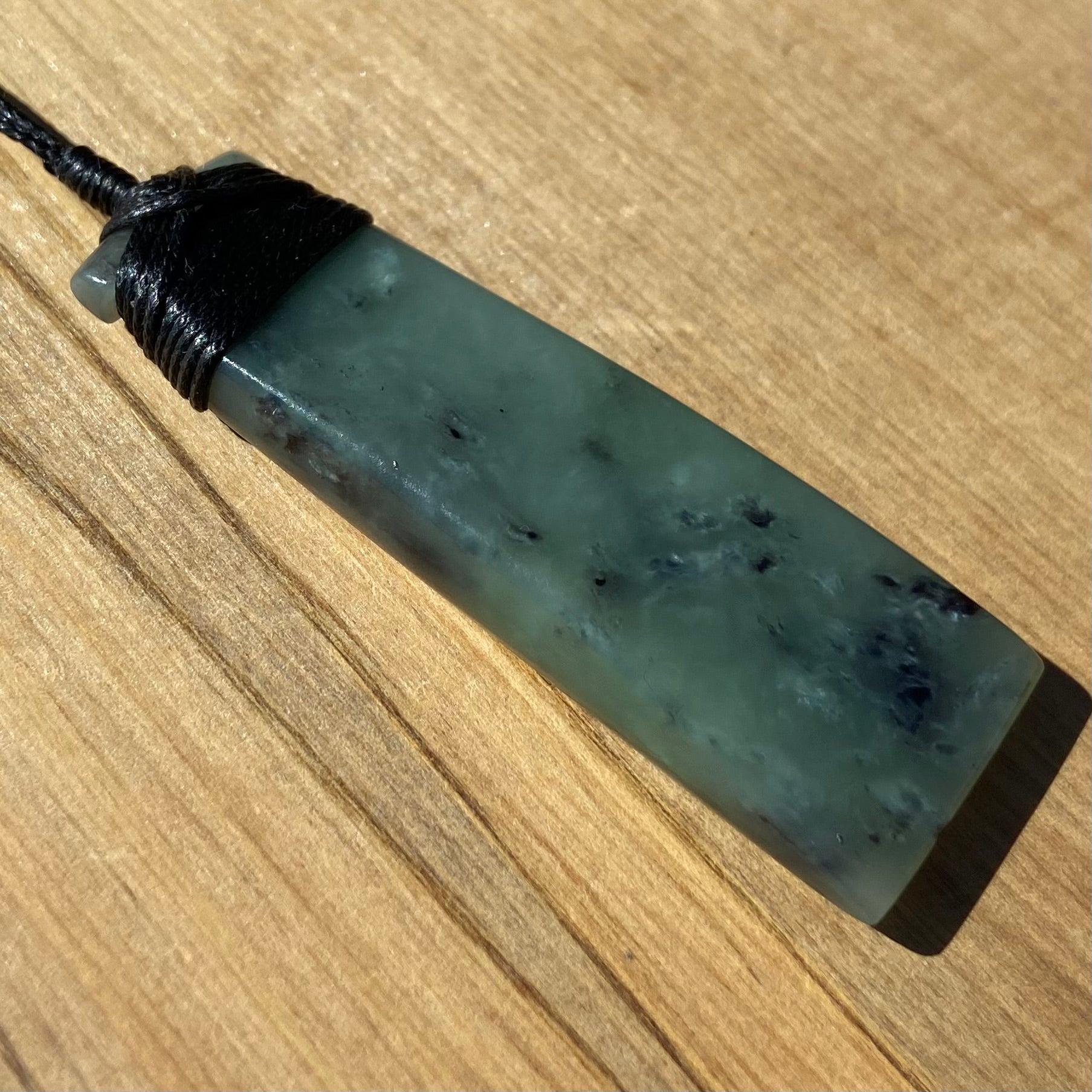 Bound toki pendant hand-carved from New Zealand inanga pounamu (greenstone). Angle.