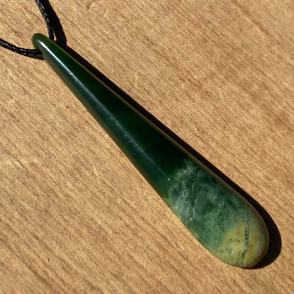 Roimata (teardrop) pendant hand-carved from New Zealand Marsden Flower Jade/ pounamu (greenstone).  Angle.