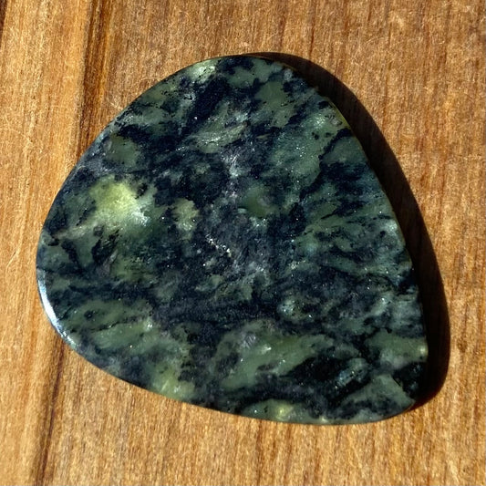 Guitar pick hand-carved from New Zealand Douglas Creek pounamu (greenstone). Front.