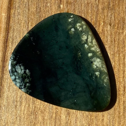 Guitar pick hand-carved from New Zealand tangiwai pounamu (greenstone). Front.