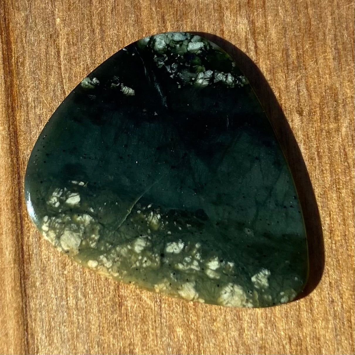 Guitar pick hand-carved from New Zealand tangiwai pounamu (greenstone). Back.